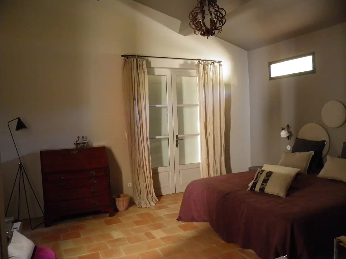 Camera di un gîte con letto matrimoniale, tende e pavimento in cotto