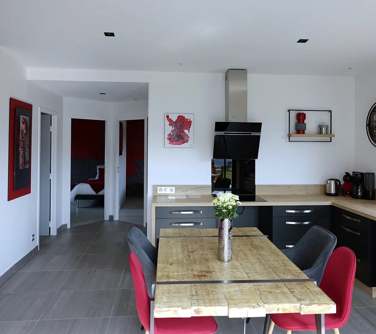 Cucina a vista attrezzata con piano cottura, cappa e tavolo in legno