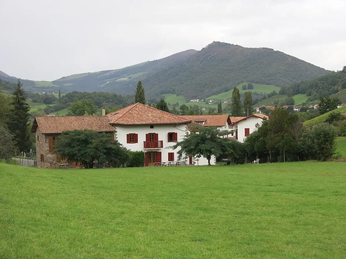 Rural gîte with red shutters in the Basque countryside, surrounded by meadows