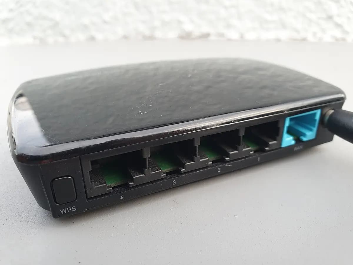 Arrière d'un routeur Wi-Fi noir avec quatre ports réseau, un port WAN bleu et un bouton WPS